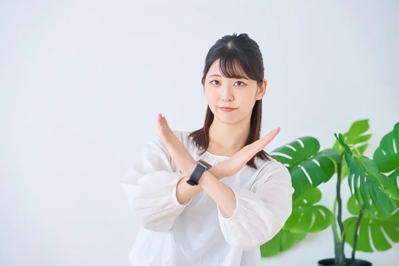腕で×印を作る女性