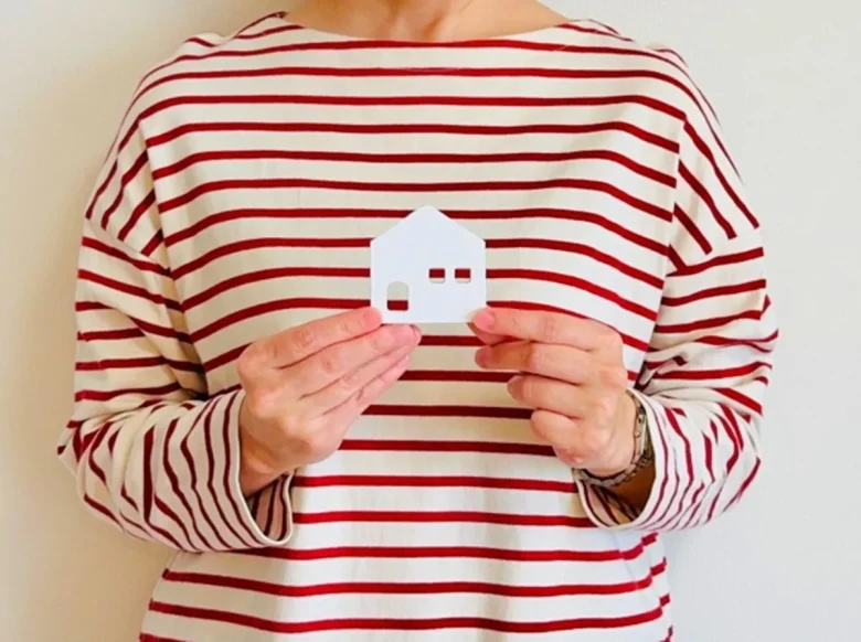 白い家の模型を持つ女性